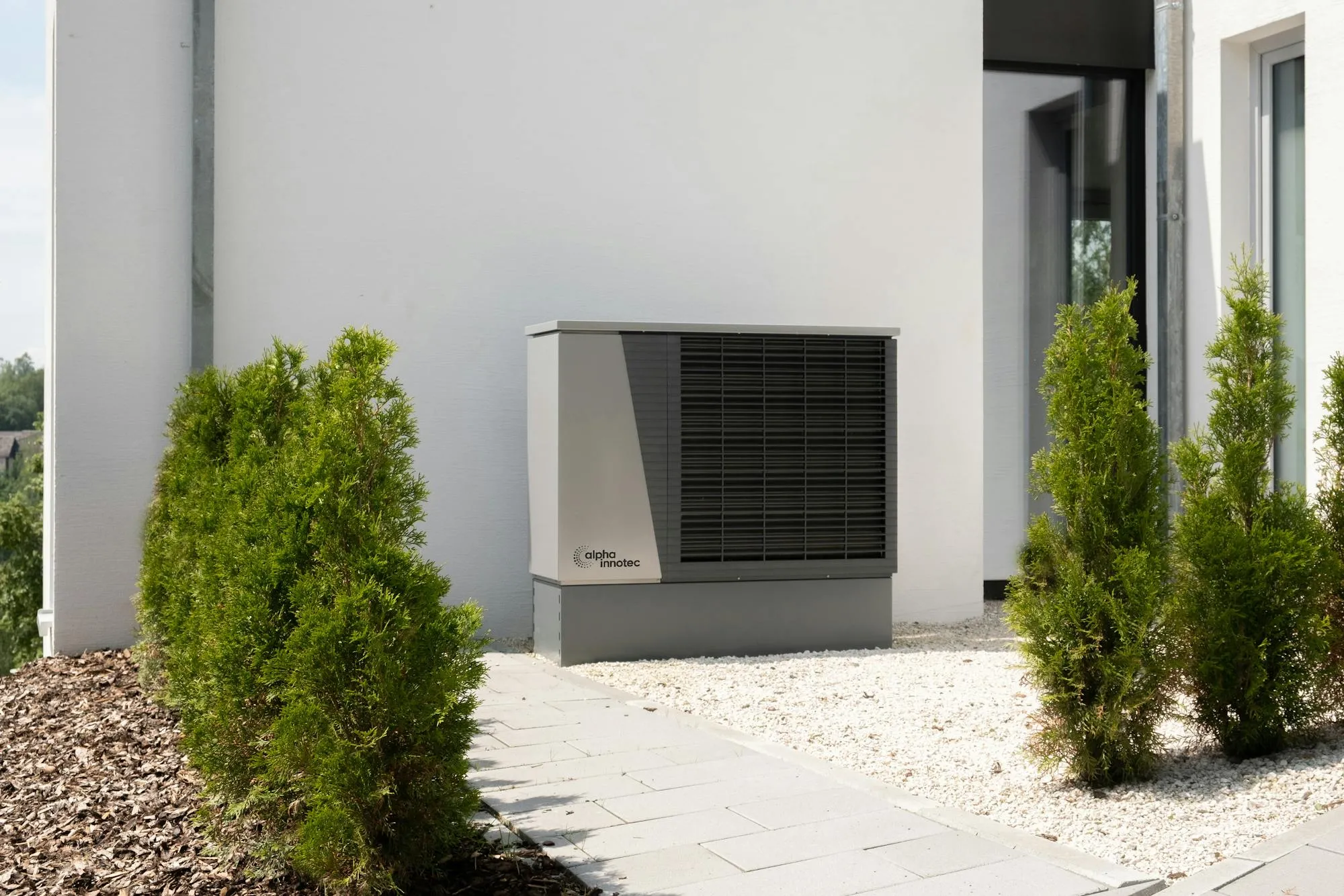 Air source heat pump unit installed against the side of a modern home